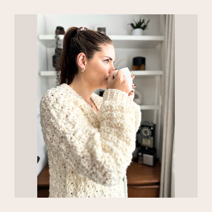 cat kemble sipping a cup of coffee gazing out of a bright window wearing lemon peel cardigan