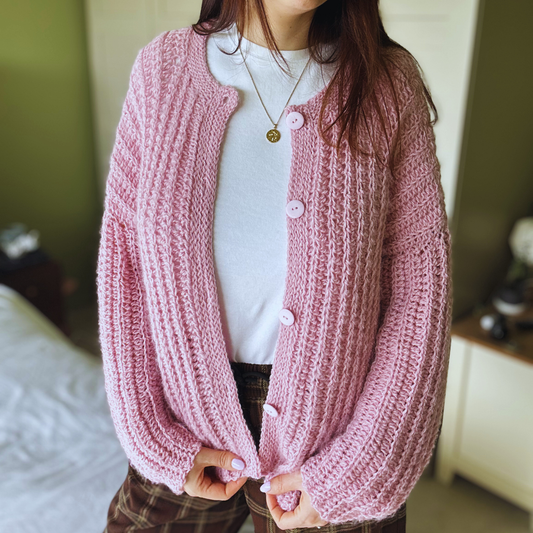 Person wearing a pink knitted cardigan in an indoor setting